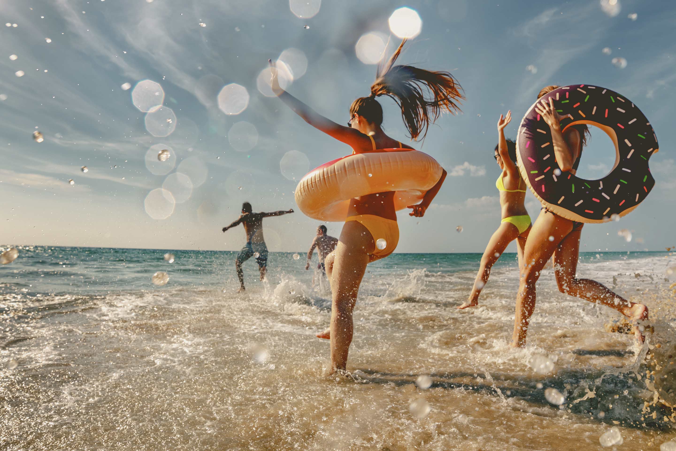 Eine Gruppe von Freunden im Sommerurlaub läuft bei Sonnenschein ins Meer.